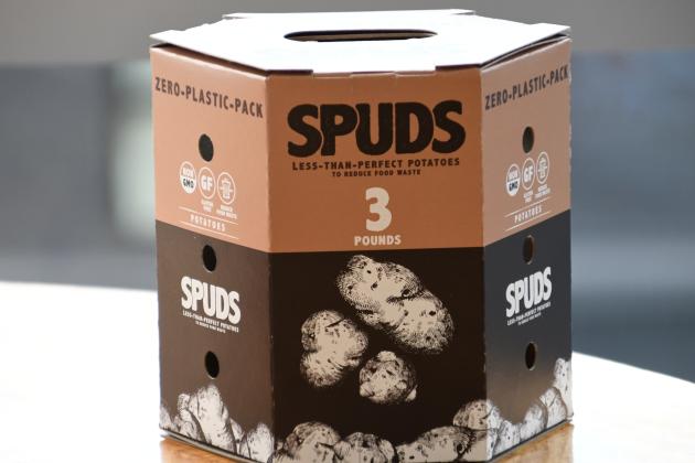 Brown, pentagonal paperboard potato packaging entitled "SPUDS Potatoes"