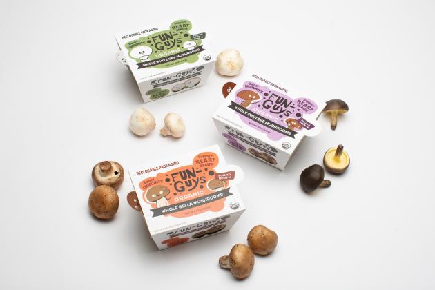 Colorful paperboard slide cover packaging for mushrooms. Mushrooms are spread out on the table among the packaging.