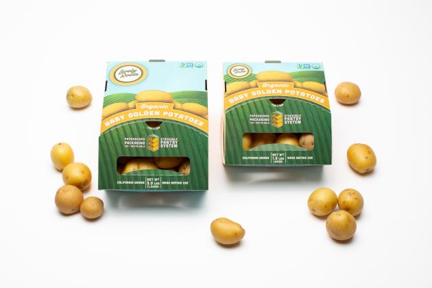 Green and blue paperboard packaging for small potatoes. Baby potatoes are placed around the packaging.